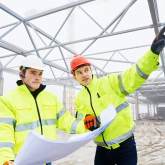 alta visibilità engineers construction foreman managers outdoors indoors at building site with blueprints